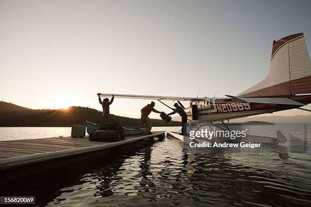 man and woman loading luggage onto float plane - hidroavión fotografías e imágenes de stock