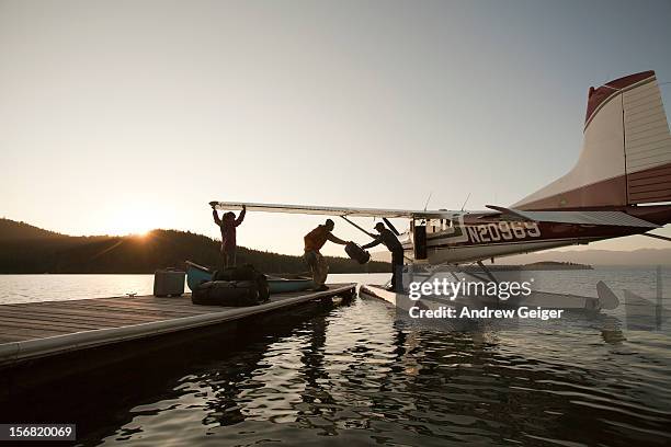 man and woman loading luggage onto float plane - seaplane stock pictures, royalty-free photos & images