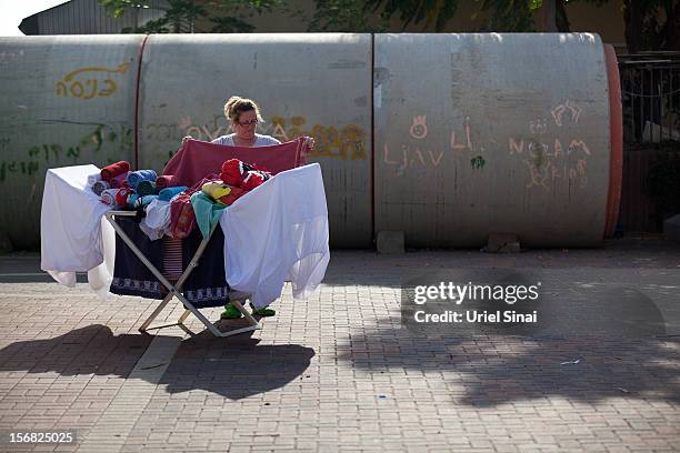 An Israeli woman does her laundry outside her house and next to a large concrete pipe used as a bomb shelter on November 22, 2012 in Nitzan, Israel....