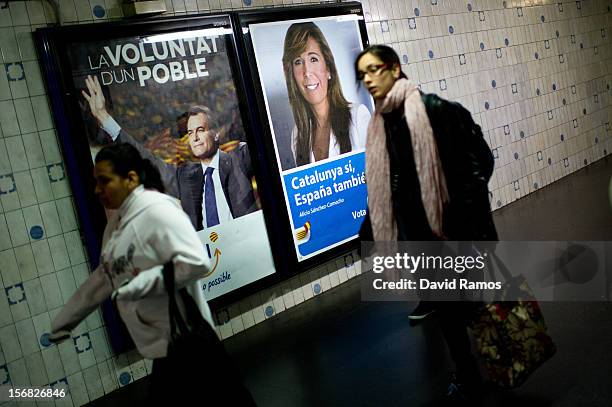 Women walk past a the Pro-independence Convergence and Union President Artur Mas poster with the slogan 'La voluntad d'un Poble', 'The will of a...