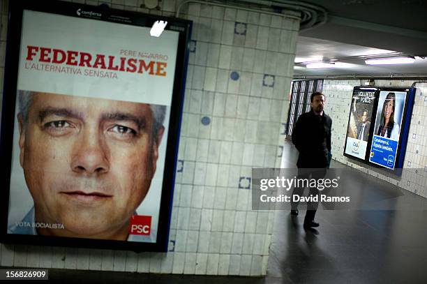 Man walks among a left-wing and Anti-separatist Socialist Party of Catalonia poster that it reads 'Federalism' a the Pro-independence Convergence and...
