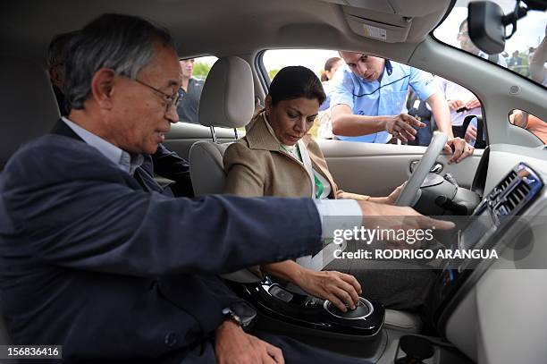 Costa Rican President Laura Chinchilla and Japanese ambassador Yoshiharu Namiki drive a car powered by solar energy during the inauguration of the...