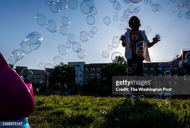 Child plays in a bubble fountain before outdoor movie night at Alethia Tanner Park in Washington, DC.
