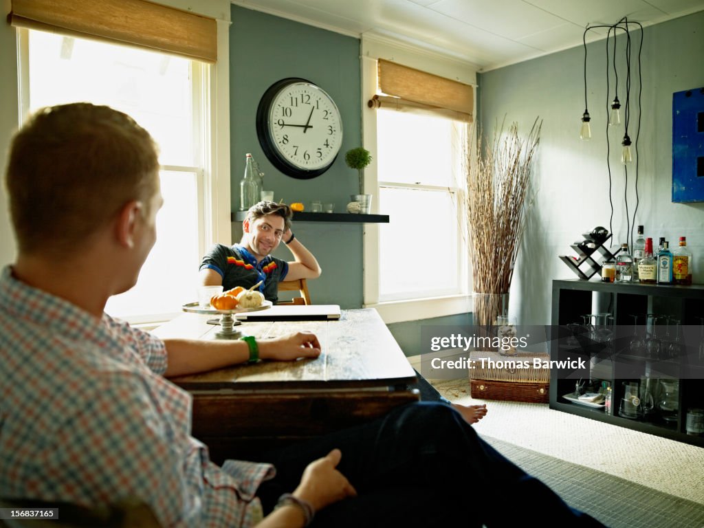 Gay couple sitting at dining room table in home