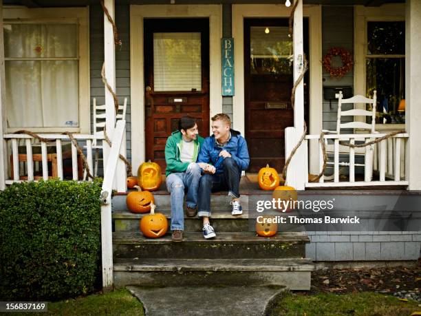 smiling gay couple holding hands on front porch - fall in seattle fotografías e imágenes de stock