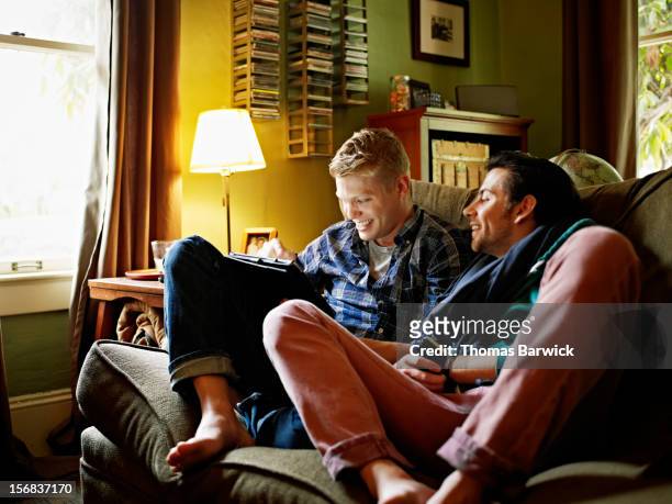 Gay couple on couch looking at digital tablet