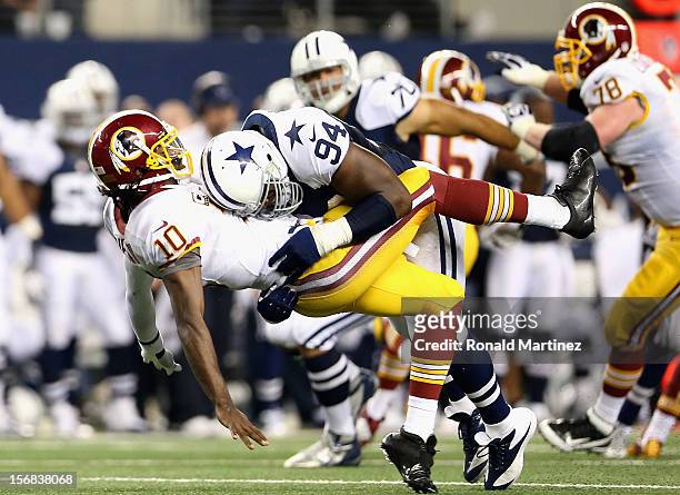 Robert Griffin III of the Washington Redskins is tackled by DeMarcus Ware of the Dallas Cowboys during a Thanksgiving Day game at Cowboys Stadium on...