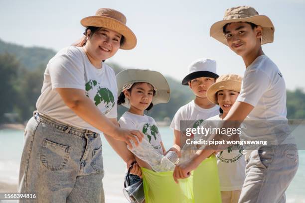 children's volunteers they are collecting plastic waste on the beach to help reduce marine pollution. - fat asian boy stock pictures, royalty-free photos & images