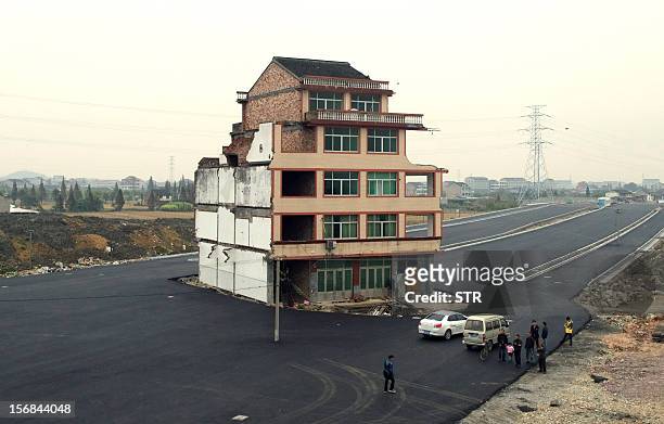 This picture taken on November 22, 2012 shows a half-demolished apartment building standing in the middle of a newly-built road thanks to a Chinese...