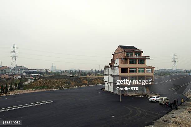 This picture taken on November 22, 2012 shows a half-demolished apartment building standing in the middle of a newly-built road thanks to a Chinese...