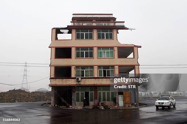 This picture taken on November 22, 2012 shows a half-demolished apartment building standing in the middle of a newly-built road thanks to a Chinese...