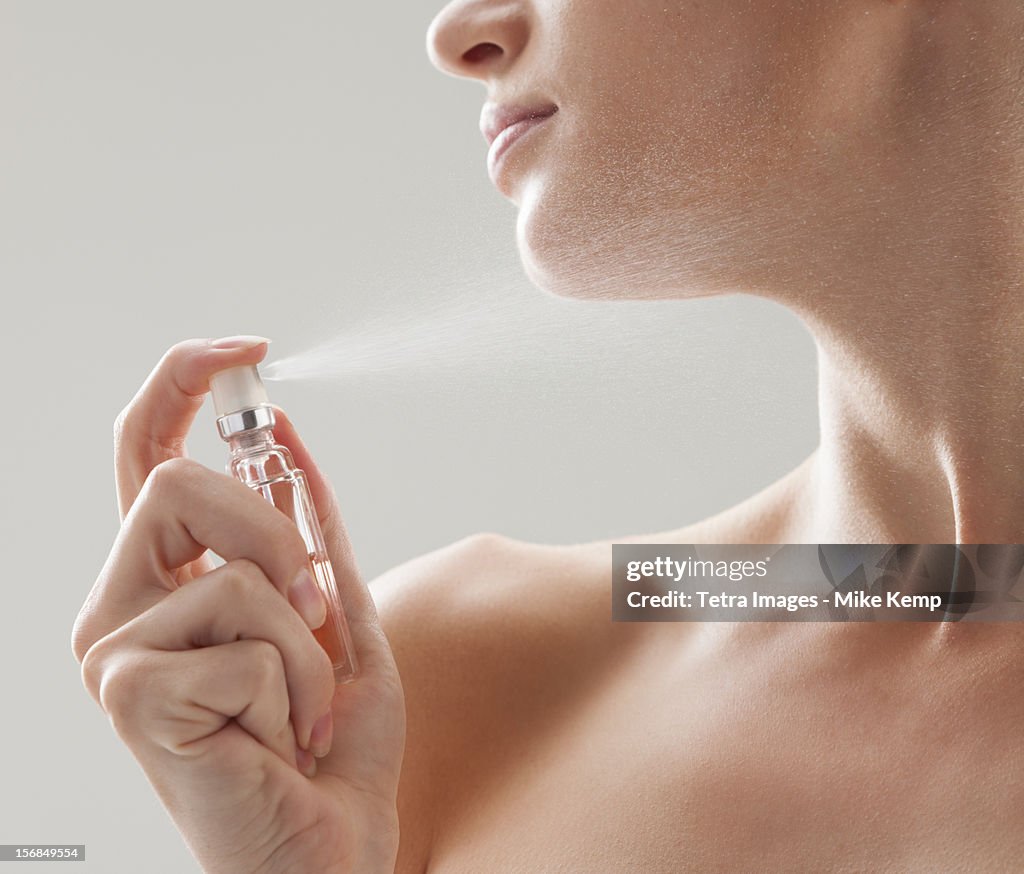 Beautiful woman spraying perfume on her neck