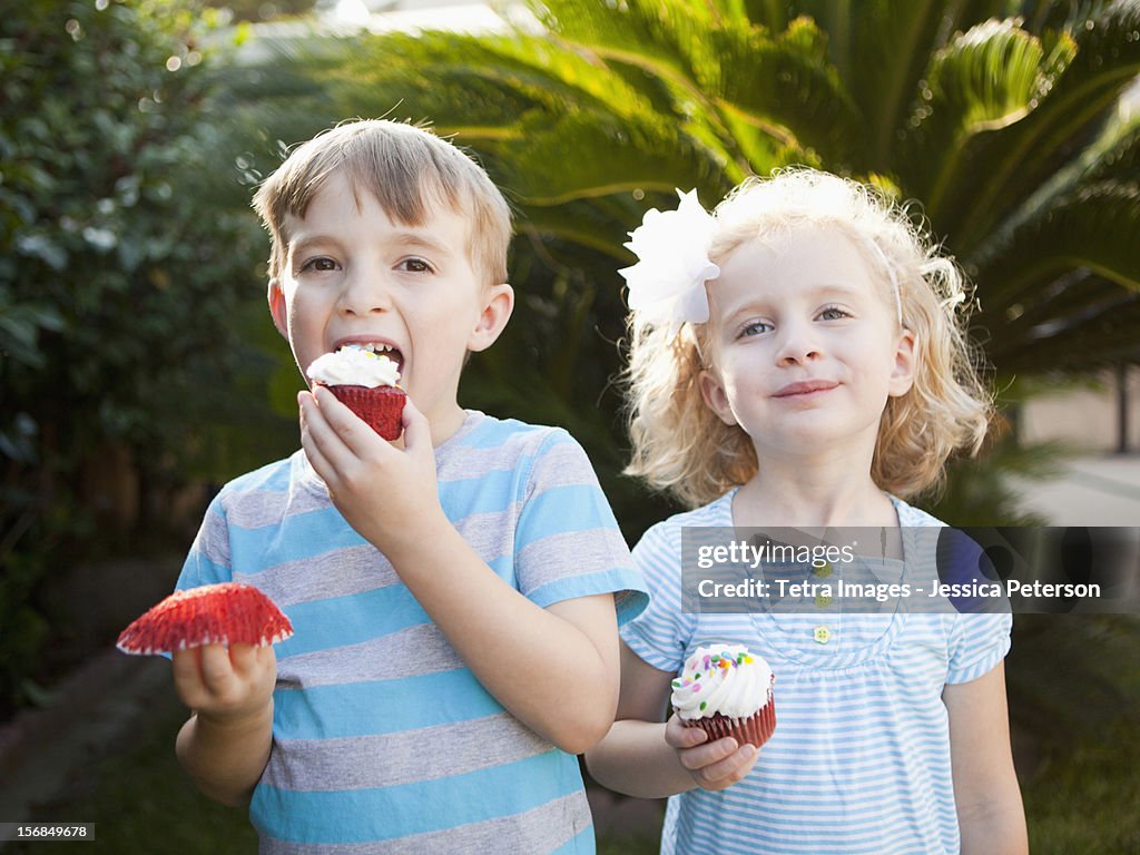 USA, California, Los Angeles, Girl and boy eating cupcakes.