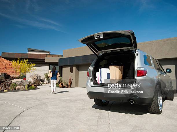 usa, utah, st. george, young woman unpacking shopping from car parked in yard - car trunk - fotografias e filmes do acervo