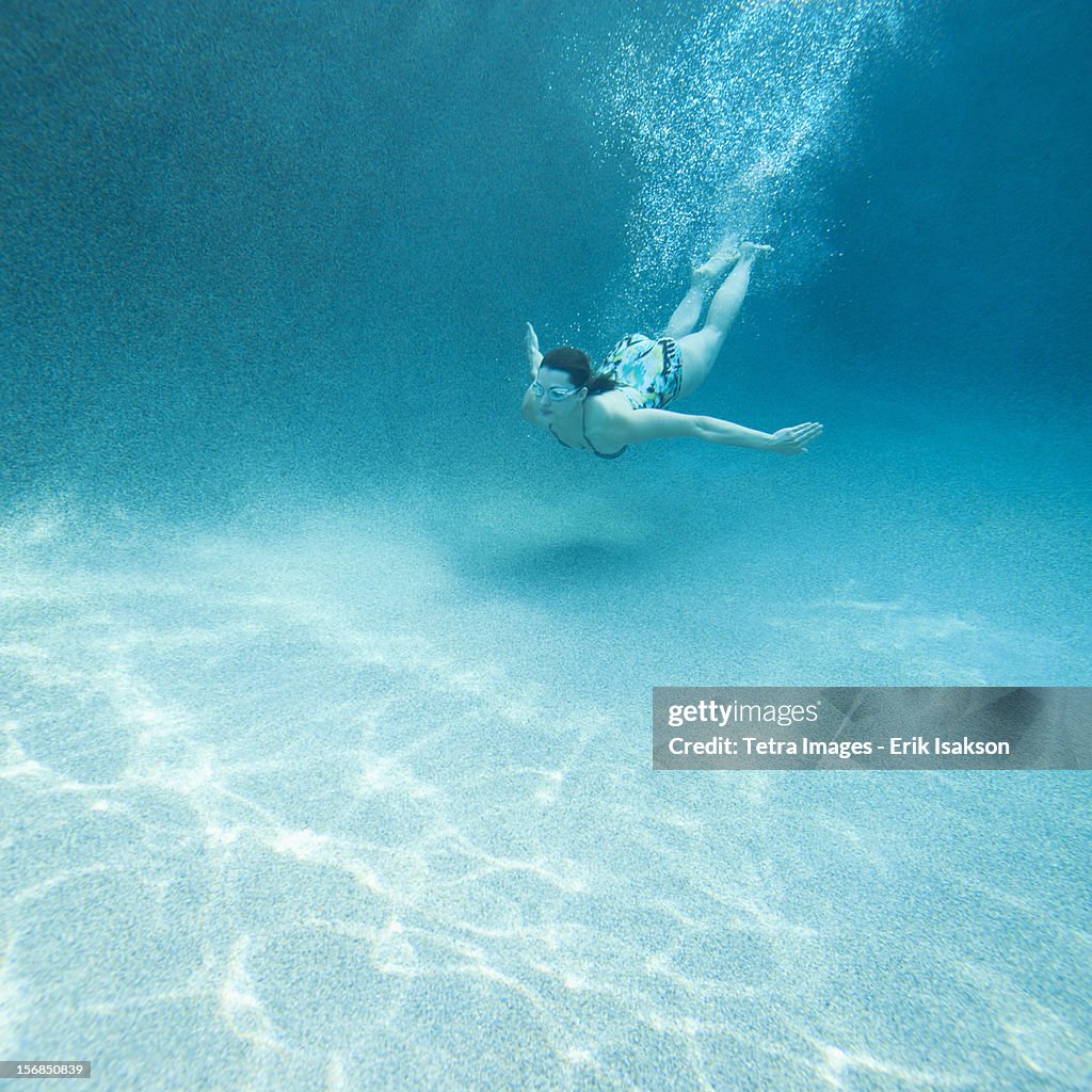 USA, Utah, St. George, Young attractive woman diving in swimming pool
