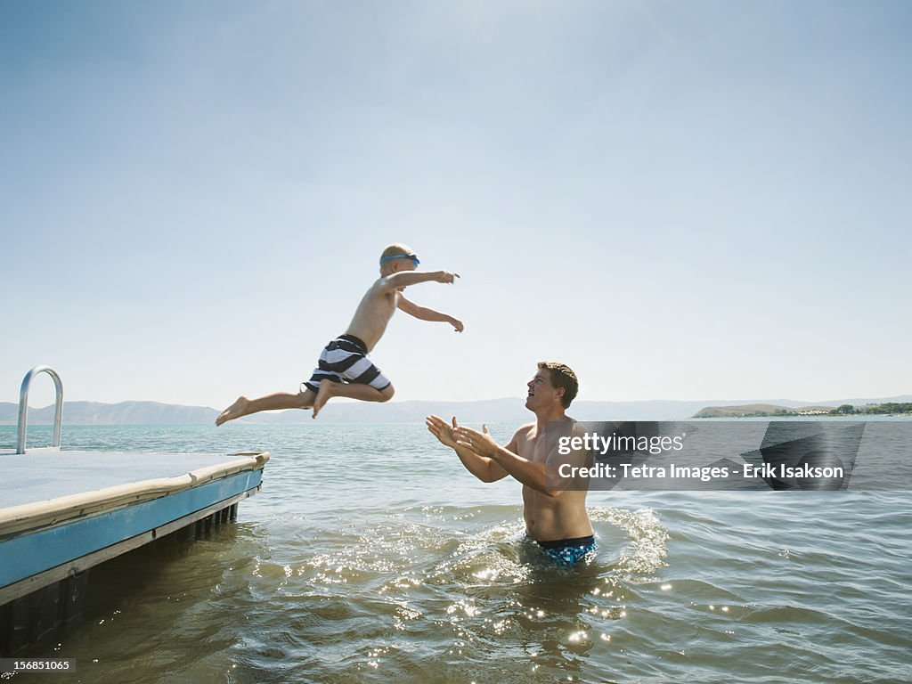 USA, Utah, Garden City, boy (4-5) jumping into lake caught by his father