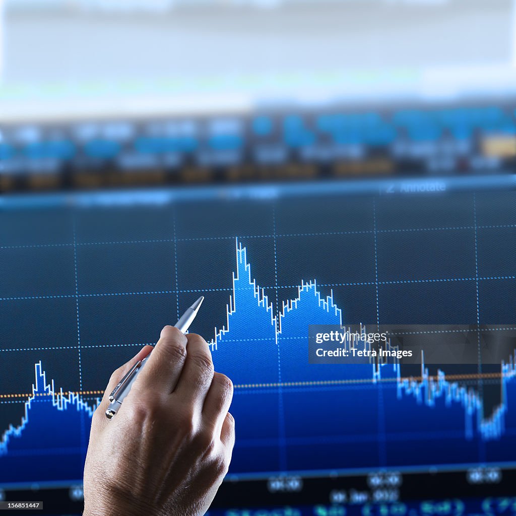 Hand pointing at financial graph, studio shot