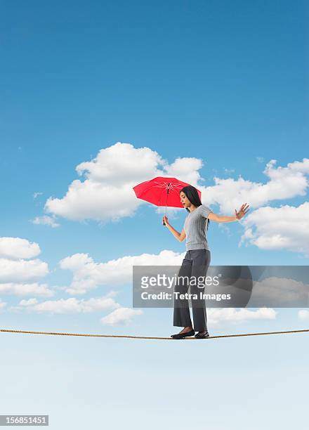 woman balancing on tightrope - drahtseilakt stock-fotos und bilder