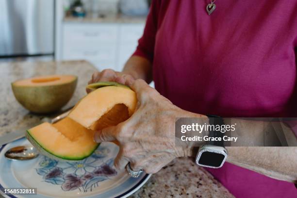 woman cuts rind from cantaloupe - カンタロープメロン ストックフォトと画像