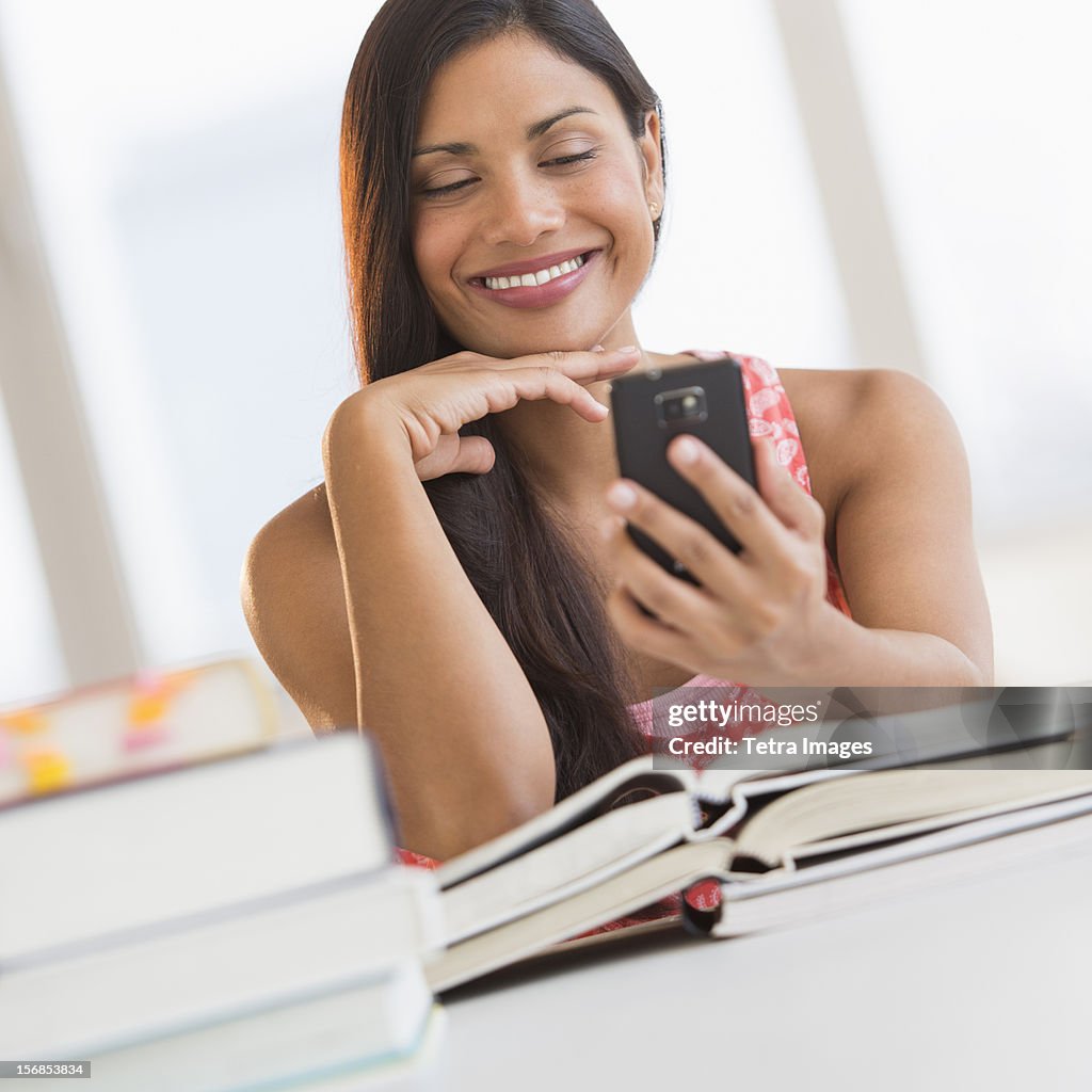 USA, New Jersey, Jersey City, Woman text messaging while studying