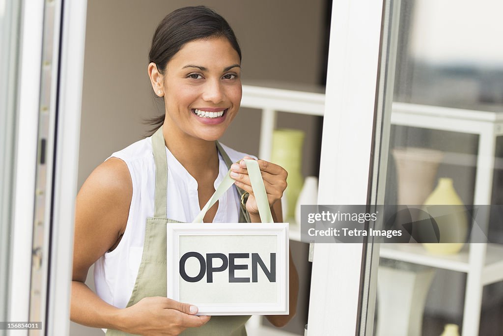 USA, New Jersey, Jersey City, Woman standing in front of store and holding open sign