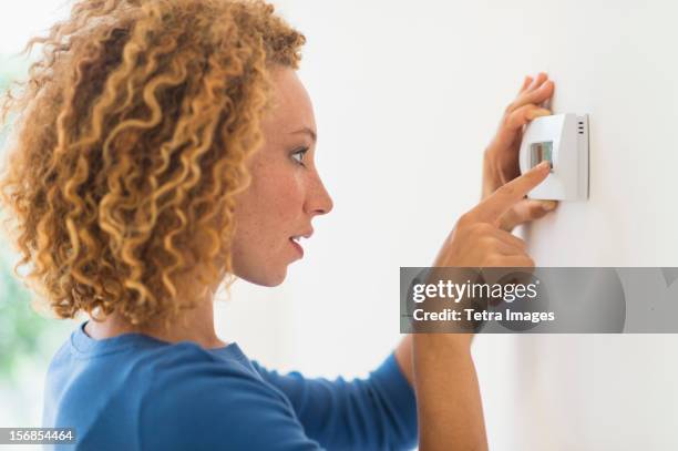 usa, new jersey, jersey city, young woman setting air conditioning - thermostat stock pictures, royalty-free photos & images