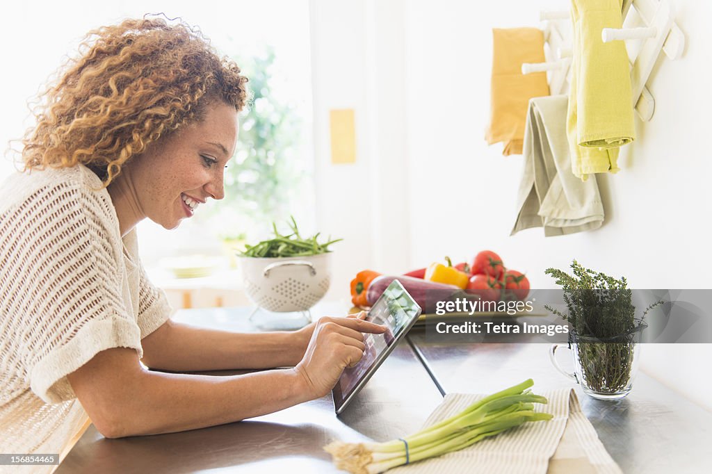 USA, New Jersey, Jersey City, Young woman using digital tablet in kitchen