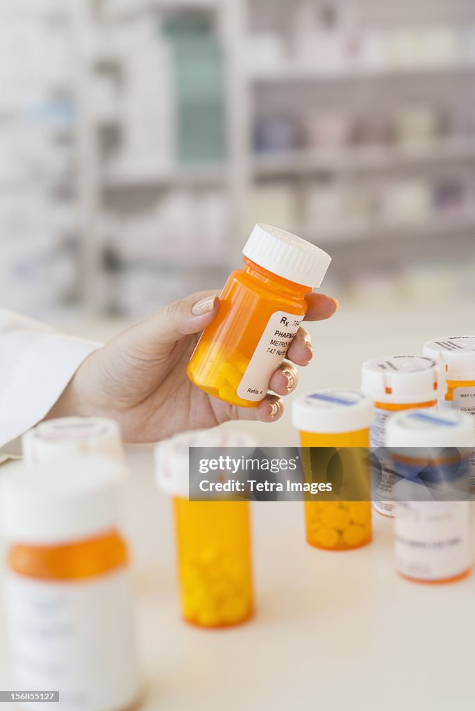 USA, New Jersey, Jersey City, Pharmacist holding pill bottle