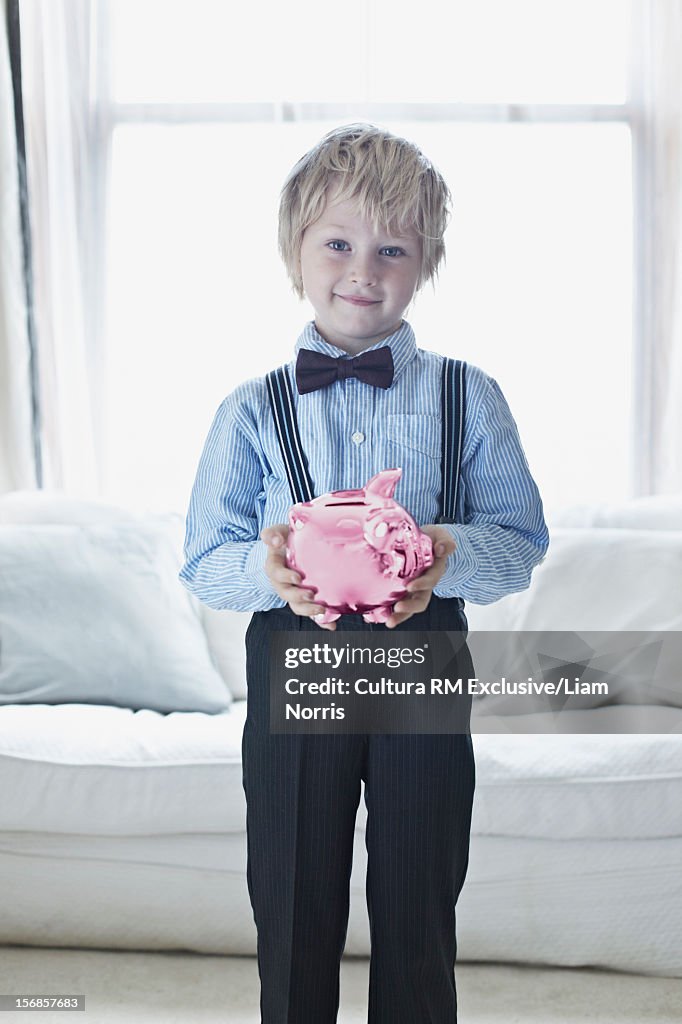 Smiling boy in suit with piggy bank