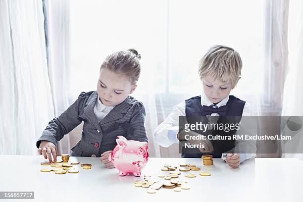 children in suits counting gold coins - blonde girl piggy bank stock-fotos und bilder