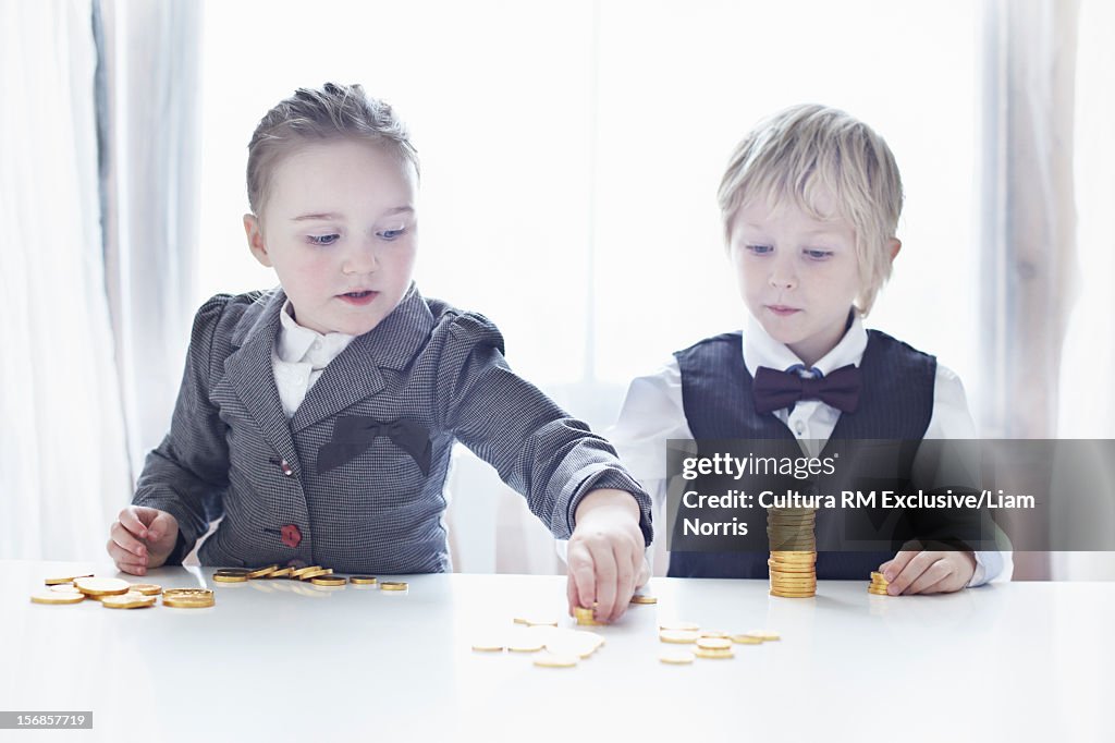 Children in suits counting gold coins