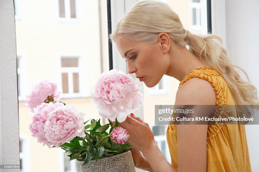 Woman smelling flowers in window