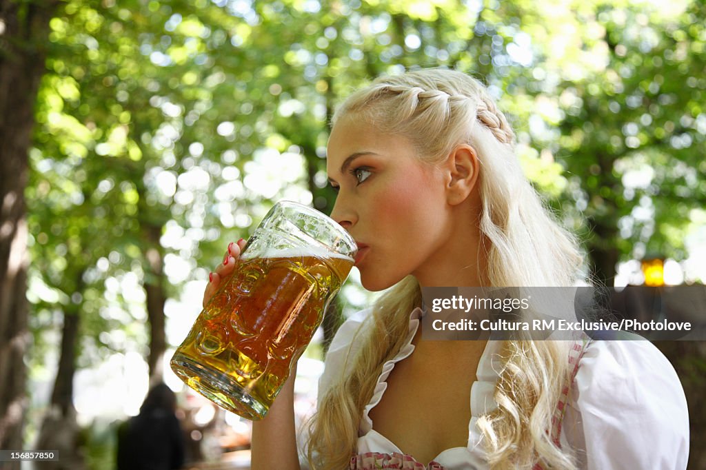 Woman drinking mug of beer outdoors
