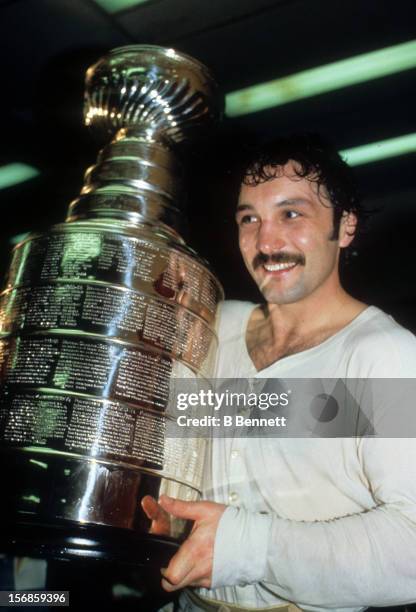 Bryan Trottier of the New York Islanders smiles while he holds the Stanley Cup Trophy after one of the Islanders Stanley Cup victories in the early...