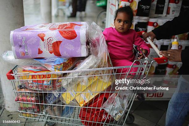 Young girl sits in a shopping trolley as families stock up with provisions as businesses get back to normal in the Israeli border town of Sderot on...