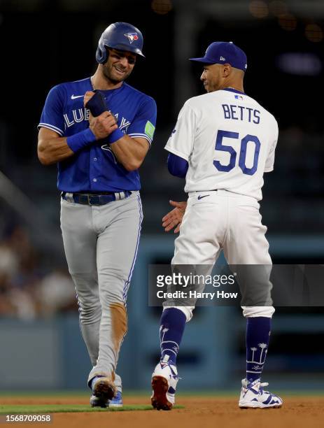 Kevin Kiermaier of the Toronto Blue Jays laughs as he walks past Mookie Betts of the Los Angeles Dodgers after a force out during the fifth inning at...