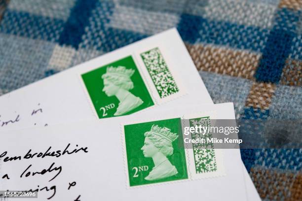 Barcoded Royal Mail 2nd class postage stamps depicting the head of Queen Elizabeth II used on two postcards on 29th July 2023 in St Dogmaels, Wales,...