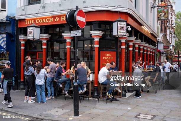 People outside enjoying a Summer afternoon drink at The Coach & Horses pub on the corner of Greek Street and Romilly Street in Soho on 9th July 2023...