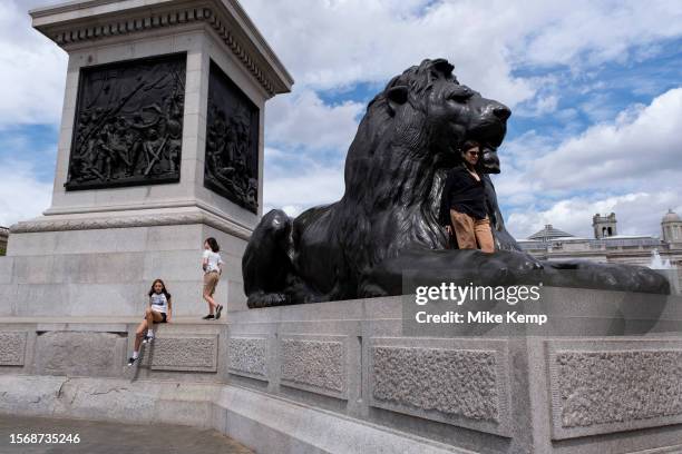 Tourists and visitors at Trafalgar Square climb up to enjoy the giant Landseer Lion statues which sit at the base of Nelson's Column on 10th July...