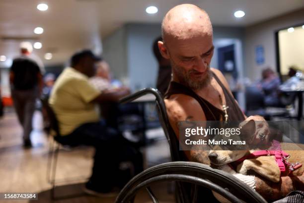 Cue Ball sits with his dog Baby Girl in the Justa Center, a cooling center for those 55 and older who are homeless, amid the city's worst heat wave...