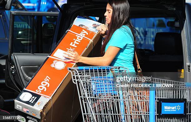 Samantha Ortiz struggles to put a newly purchased basketball hoop set from Walmart into her vehicle as Walmart employees and their supporters...