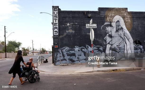 Roni and Cue Ball, who are both homeless, make their way toward a market amid the city's worst heat wave on record on July 24, 2023 in Phoenix,...