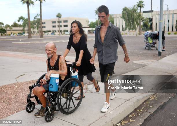 Roni and Cue Ball , who are both homeless, make their way toward a market amid the city's worst heat wave on record on July 24, 2023 in Phoenix,...