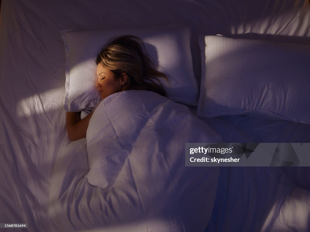 Oben Ansicht einer entspannten Frau, die nachts im Bett schläft.