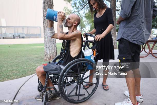 Cue Ball and Roni, who are both homeless, stop to drink water as they make their way toward a market amid the city's worst heat wave on record on...