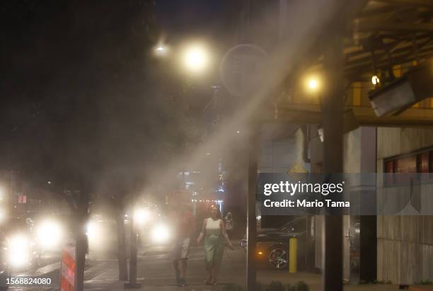 People walk toward misters amid the city's worst heat wave on record on July 24, 2023 in Phoenix, Arizona. While Phoenix endures periods of extreme...