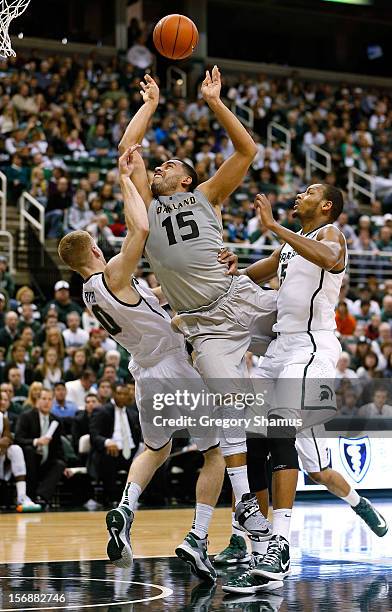 Drew Valentine of the Oakland Golden Grizzlies tries to get a shot off between Russell Byrd and Adreian Payne of the Michigan State Spartans at the...