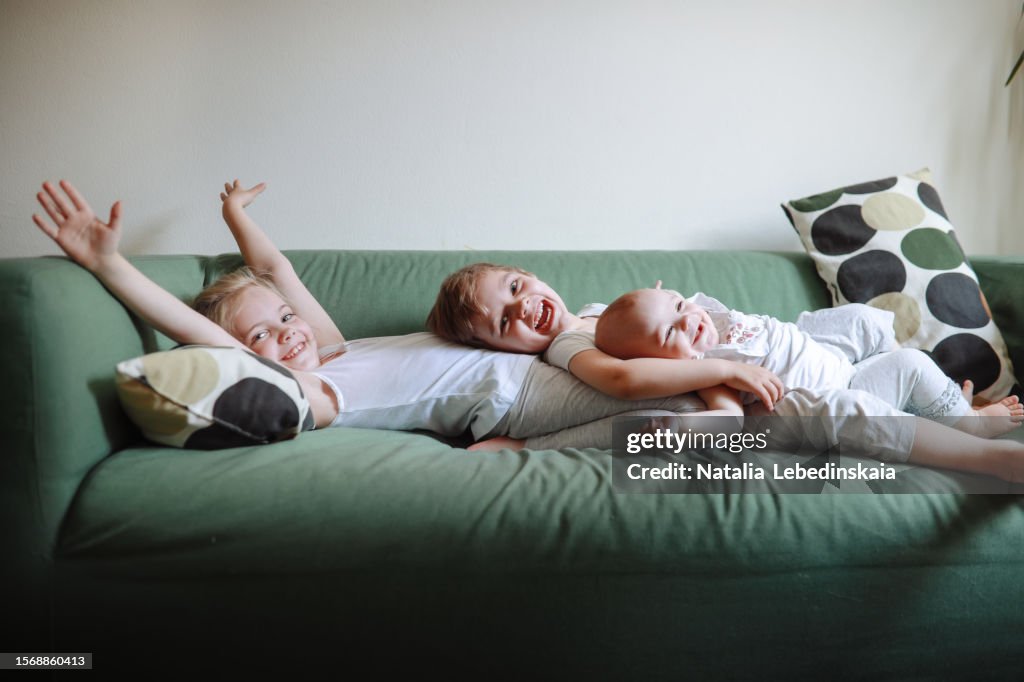 Capturing Childhood: Genuine Sibling Love and Happy Displayed on Green Sofa