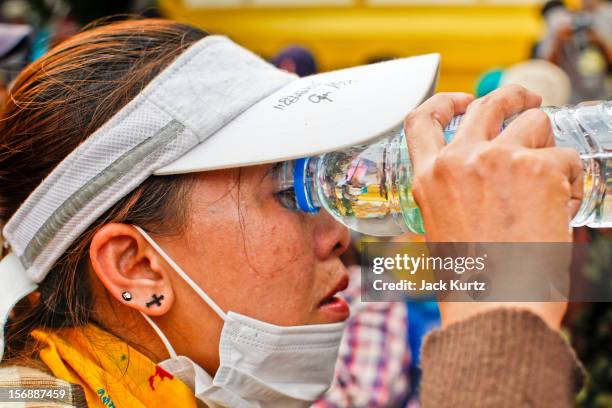 Woman tries to flush tear gas out of her eyes after Thai police gassed the crowd during a large anti government protest on November 24, 2012 in...