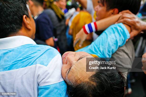 Protesters carry one of their own after she was overcome by tear gas during a large anti government protest on November 24, 2012 in Bangkok,...